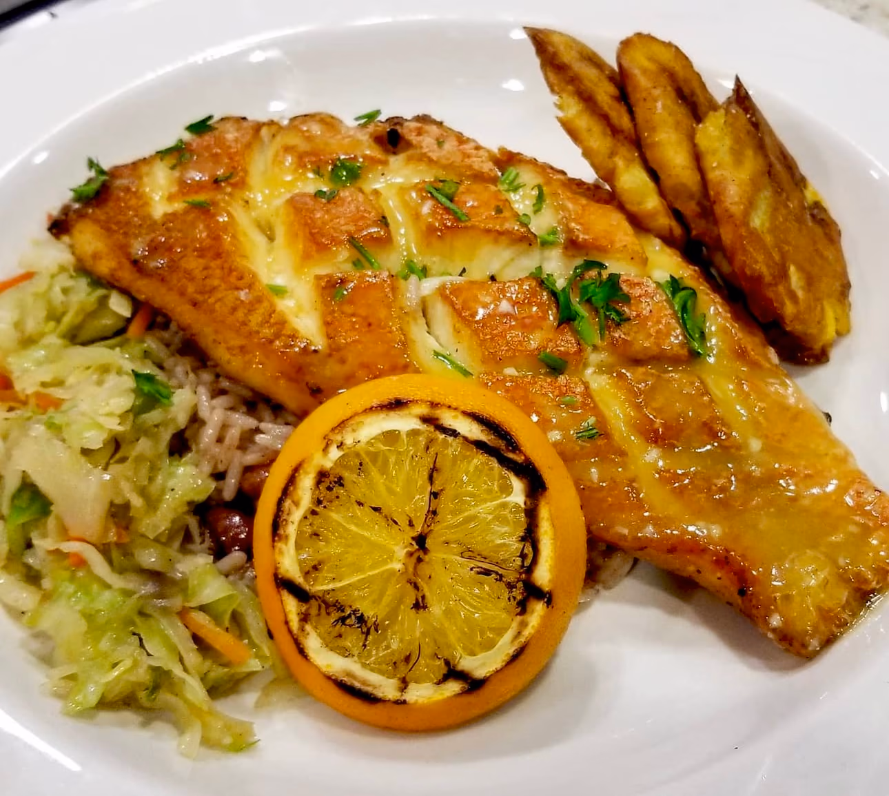 Seared fish with grilled lemon, plantains and greens
